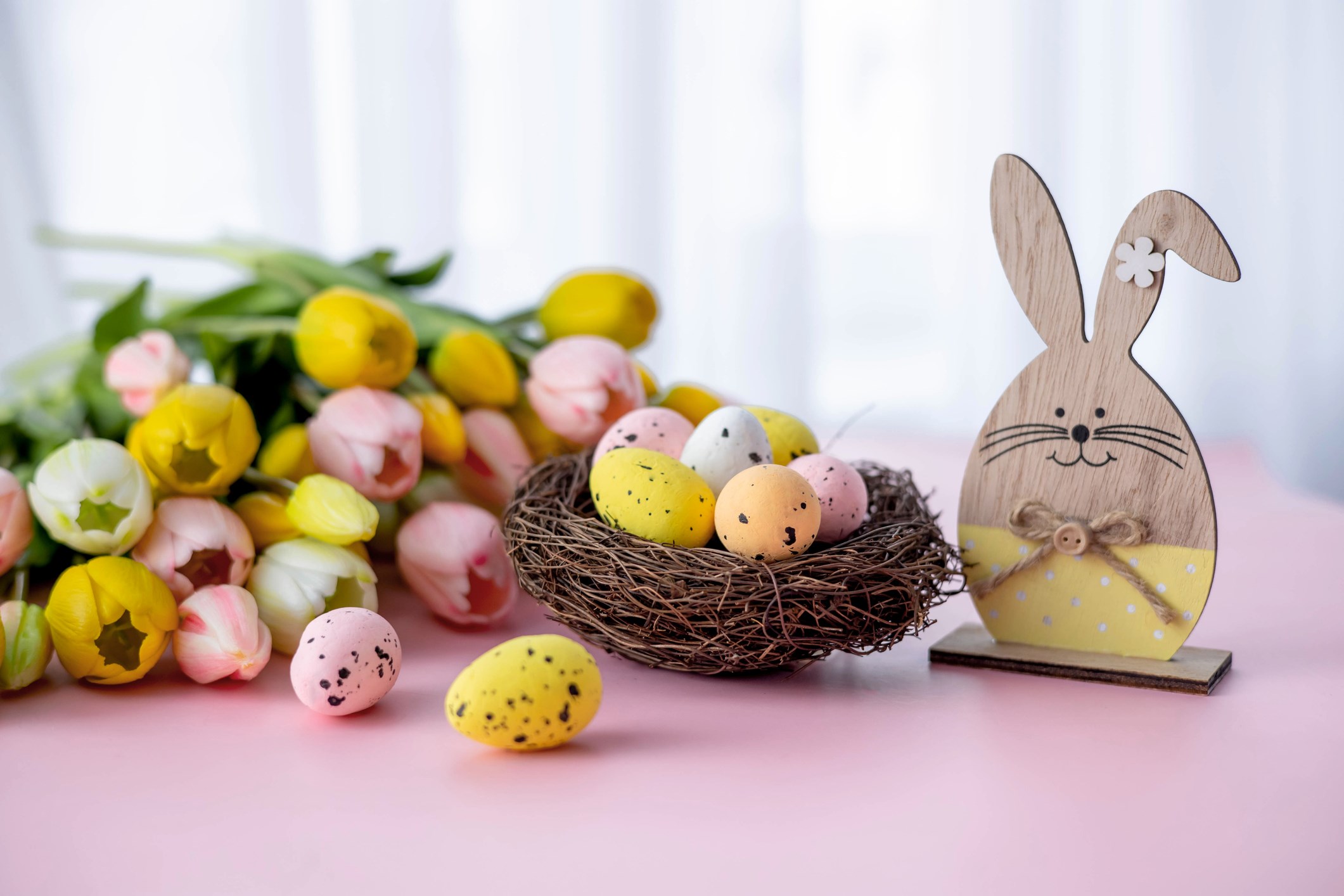 Colorful Easter eggs, tulips, and a wooden hare on a table